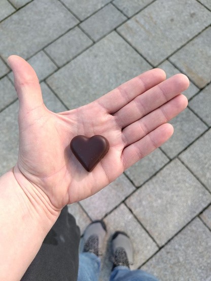 Kleines Herz aus Schokolade in einer ausgestreckten Hand.