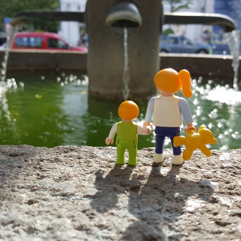 Bild mit Playmobilfiguren

Zwei Kinder stehen vor einem Brunnen. Das Wasser funkelt.