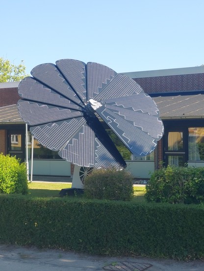 Eine Blüte aus fächerförmig montierten Solarpanelen steht im Vorgarten eines öffentlichen Gebäudes aus Samsø