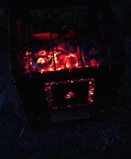Heruntergebranntes Feuer in einer Bushbox. Die Glut leuchtet rot im Dunkeln