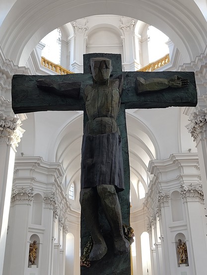 Modernes Kruzifix. Im Hintergrund ist der Innenraum einer Kirche zu erkennen.